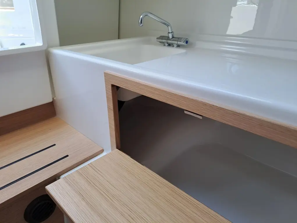 Modern kitchen sink with a sleek white basin, wooden accents, and a pull-down faucet, featuring under-counter storage.